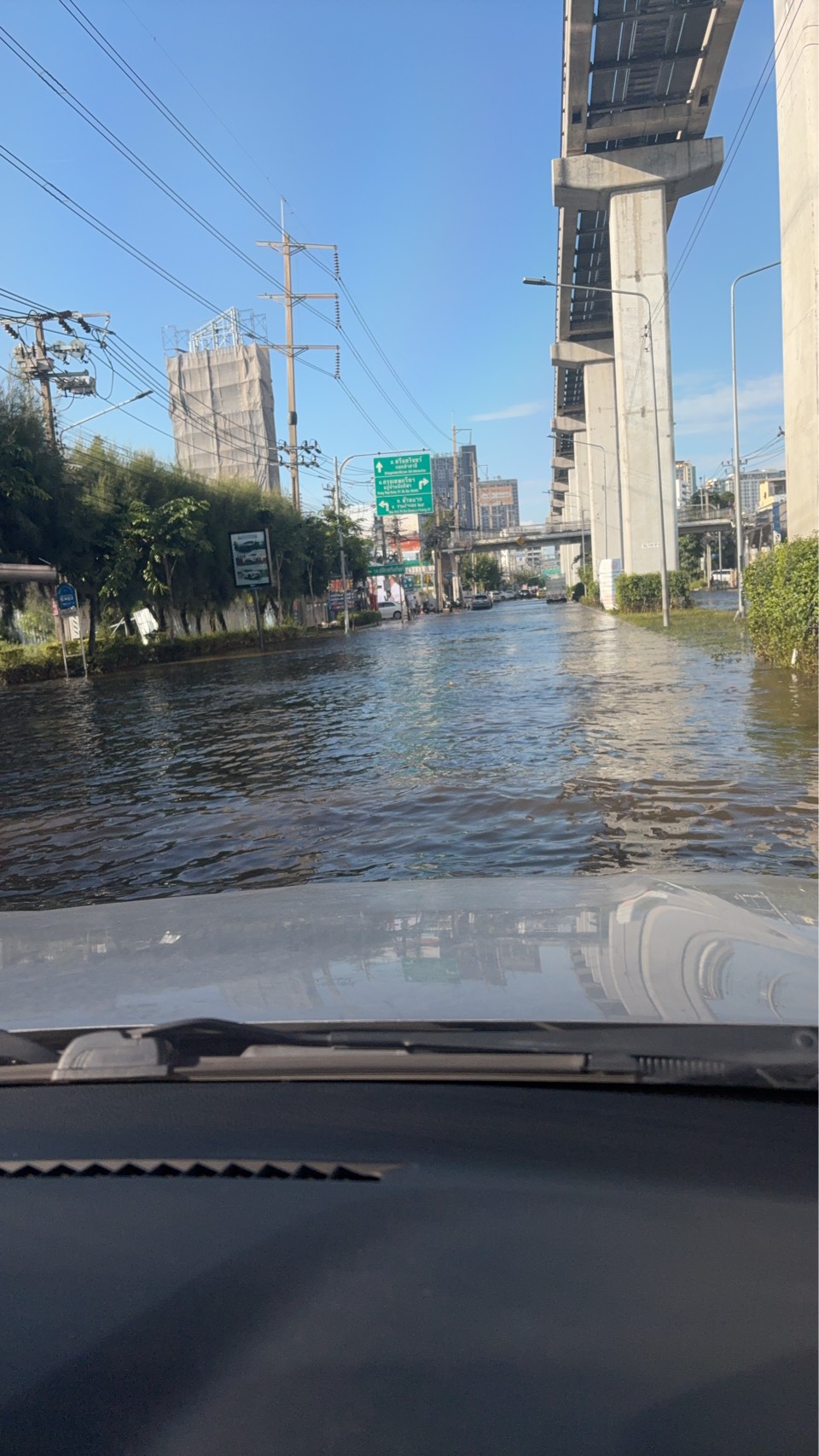 A flooded road alongside an elevated structure in Bangkok, photographed from inside a vehicle