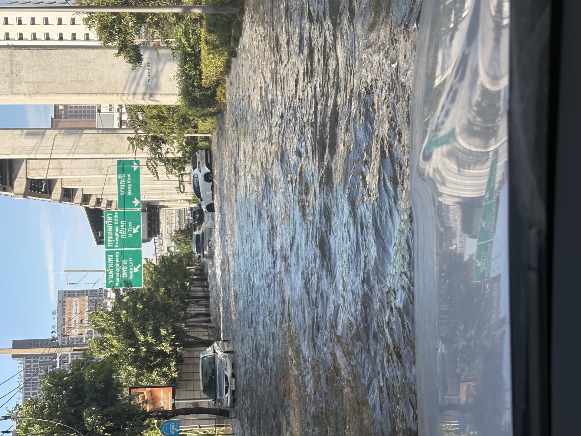 Vehicles traveling through floodwater on a road in Bangkok